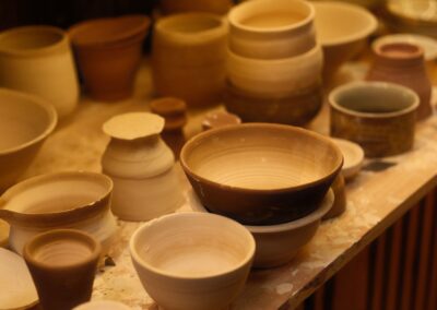 A collection of handcrafted ceramic bowls displayed in an artisan pottery studio with soft lighting.